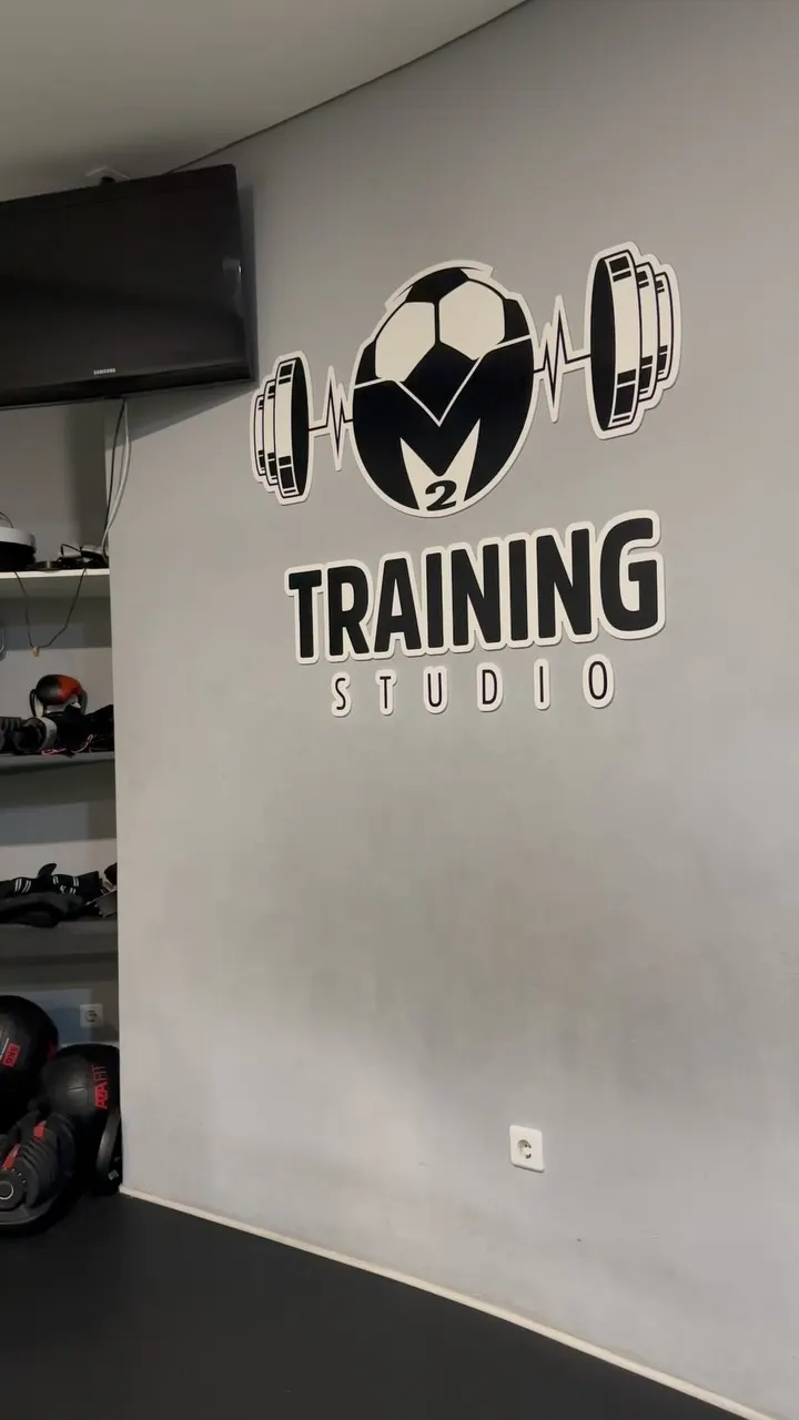 Logótipo do M2 Training Studio na parede cinzenta do estúdio